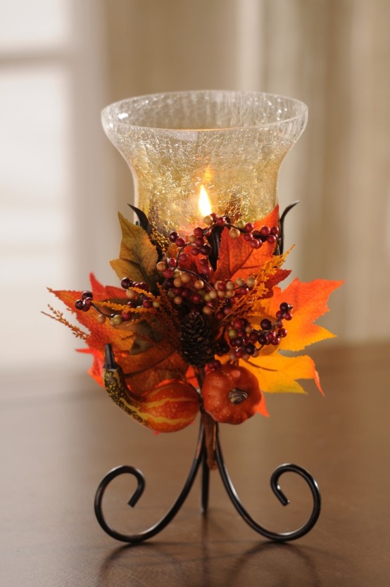 a candle in a glass candleholder decorated with bright fall leaves and berries is a lovely fall decoration to rock