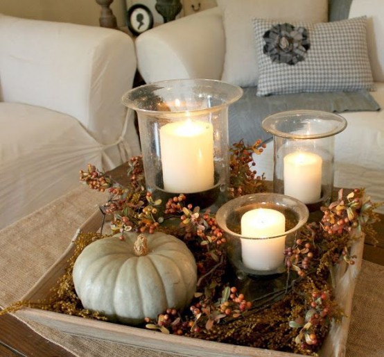 a fall arrangement of a tray with faux berries, a pumpkin and some pillar candles in glass candle holders is a chic rustic option