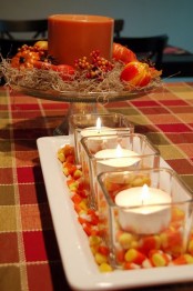 a plate with candy corn and candles in glasses is a bright fall centerpiece you can easily make last minute