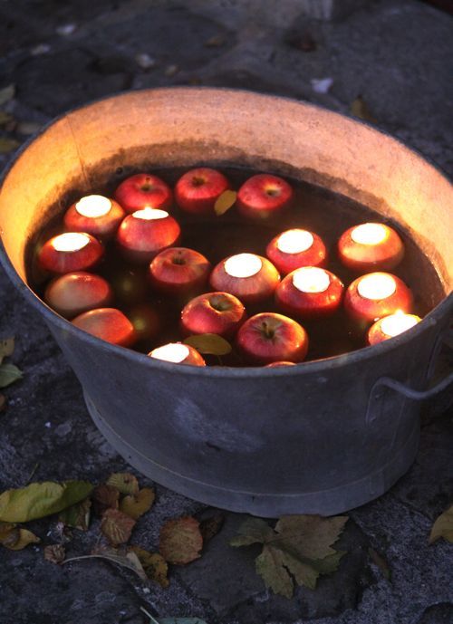 a metal bathtub with floating apples and candles in the apples to light it up is a cool arrangement for outdoors