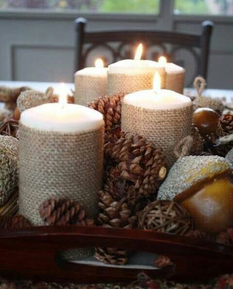 a rustic fall centerpiece of a tray with pinecones, candles wrapped with burlap and acorns is a lovely idea for the fall