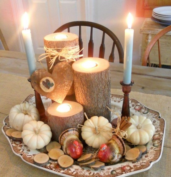 a rustic fall arrangement of mini pumpkins, wood slices, turkeys, tree stumps with candles and long and thin candles
