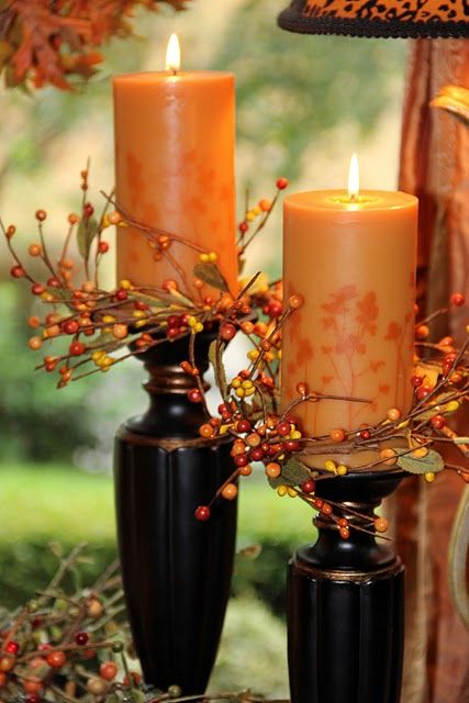 bright orange candles with faux berries placed in dark wooden candleholders will give a rustic fall feel to the space