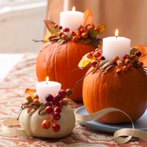 pillar candles in pumpkins with berries and leaves are very bright, cozy and fall-like