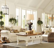 a white barn living room with white seating furniture, lots of potted greenery, a jute rug, lamps and candles is a very lovely idea