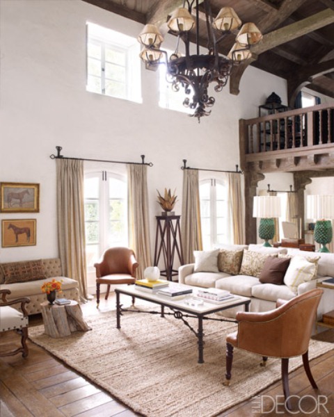 an elegant and chic barn lviing room with neutral seating furniture in vintage style, a low coffee table, a vintage chandelier and some pretty artworks