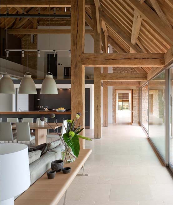 a contemporary barn living room with wooden beams and pillars, with sleek contemporary furniture, chic pendant and table lamps