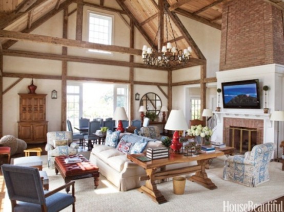 a real barn living room with wooden beams, a fireplace clad with brick, neutral seating furniture, wooden consoles and tables and a round mirror is a lovely idea