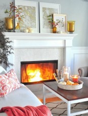 a printed pillow, a red blanket, amber glass candle holders, fall leaf arrangements
