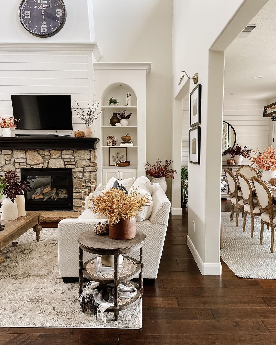 fall colored pillows, a bright orange leather ottoman and fall leaf arrangements add a fall touch to the space