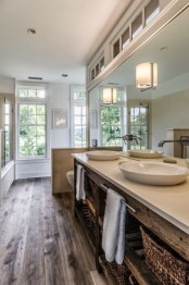 a cozy farmhouse bathroom with wooden floors, a stained wooden vanity and a half wall to divide the bathring space