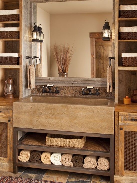 an earthy tone farmhouse bathroom with tiles, wooden storage units on both sides and a concrete sink
