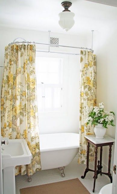 a small farmhouse bathroom with yellow printed curtains, a vintage sink and clawfoot bathtub a small farmhouse bathroom with yellow printed curtains, a vintage sink and clawfoot bathtub