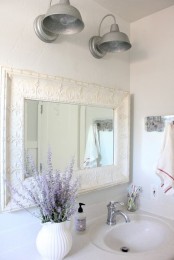 an elegant white farmhouse vanity and a vintage mirror frame plus some lavender in a vase