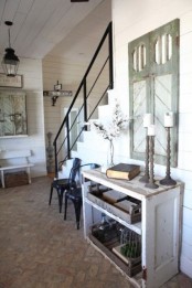 a vintage farmhouse entryway with a wooden console, a vintage shutters on the wall and pendant lamps