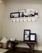a monochromatic farmhouse entryway with a dark staiend bench, a white rack, a gallery wall with family pics on the rack