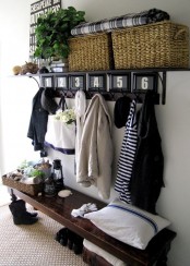 a modenr rustic entryway with a dark vintage bench, a rack with basket boxes and a jute rug