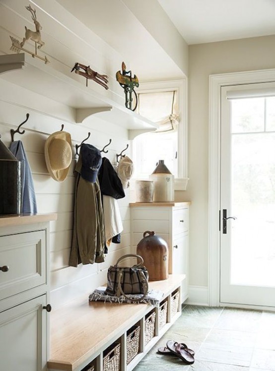 a neutral farmhouse entryway clad with white wooden planks, a built-in bench with woven boxes and much natural light