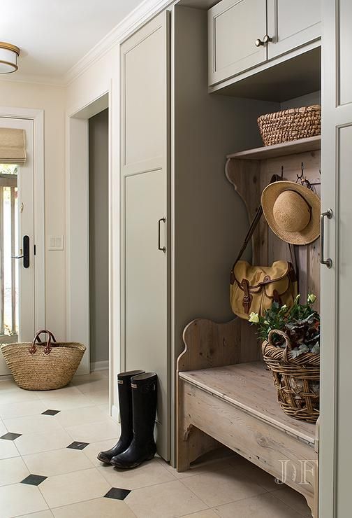 a farmhouse entryway with a large grey storage unit, a built-in wooden carved bench and a mosaic tile floor