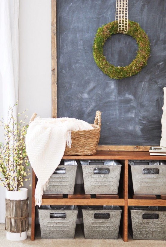 a simple farmhouse entryway with a large bench with metal boxes for storage and a chalkboard with a wreath on it