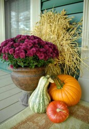 farmhouse porch decor with gourds, pumpkins, purple blooms in a vintage urn and a wheat arrangement placed behind them