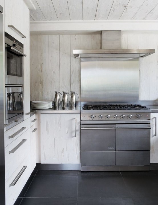 a white wood chalet kitchen with stainless steel appliances is a cool idea for a contemporary chalet