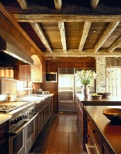 a cozy chalet kitchen all clad with wood, with wooden beams on the ceiling, with rustic and vintage furniture and built-in lights