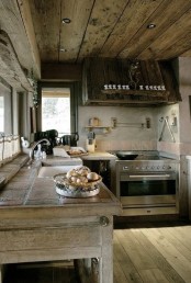 a rough chalet kitchen all clad with neutral reclaimed wood, with a rough wooden hood, with tiles on the countertops