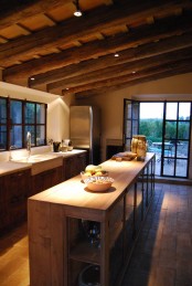 a chalet kitchen done with a wooden ceiling with beams, with matching furniture and whiet stone countertops