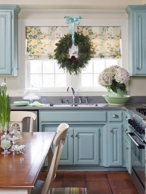 an evergreen Christmas wreath with pinecones and blue ribbons, white blooms in a vase for a holiday feel in the kitchen