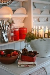 red tin cans, pinecones, a porcelain soup bowl with evergreens and candles for Christmas kitchen decor