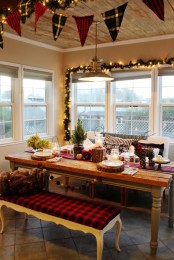plaid buntings, evergreen and lights garlands, mini Christmas trees, tree stumps and a plaid upholstered bench