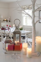 a frozen white Christmas tree, candles, candle lanterns and red touches for a holiday feel
