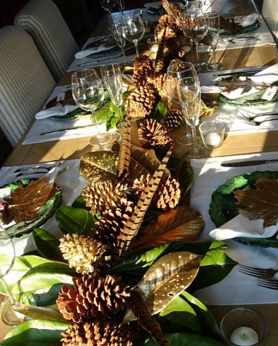a Thanksgiving table runner of feathers, foliage and large pinecones is a chic rustic idea