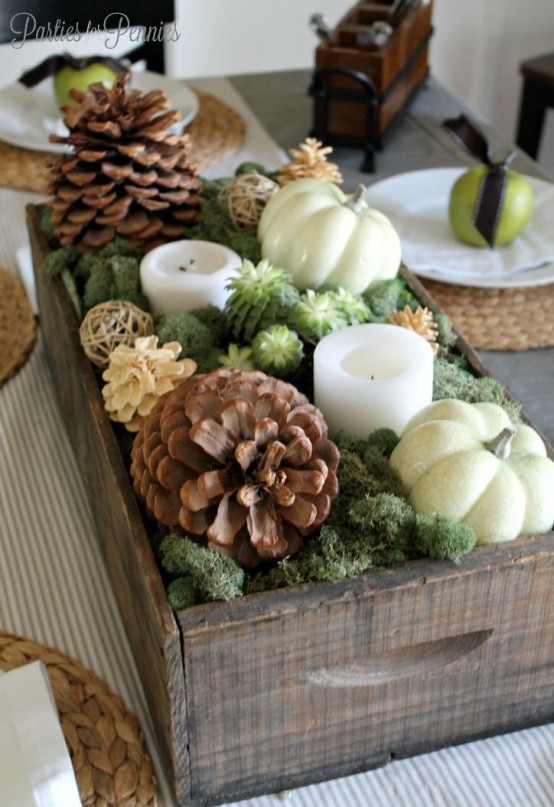 a gorgeous fall centerpiece of a crate with moss, succulents, candles, usual and bleached pinecones and pumpkins