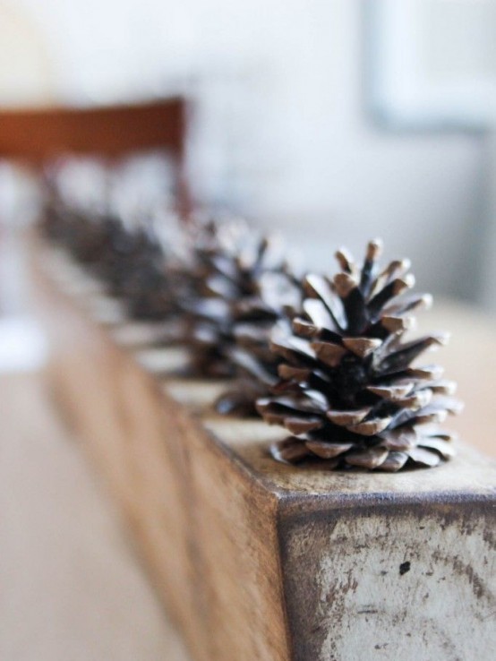 a rough rustic centerpiece made of a wooden slab and pinecones inserted into it for a cozy feel