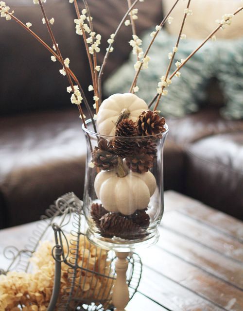 a casual clear vase centerpiece of pinecones, white pumpkins and blooming branches for the fall