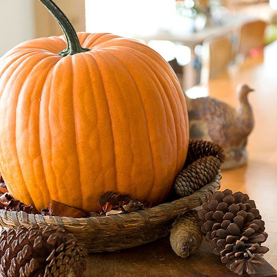 a bold fall centerpiece of a wicker bowl with pinecones and a large orange pumpkin will bring a rustic feel to the space