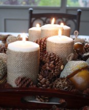 a stylish centerpiece of a tray with pinecones, faux acorns and candle wrapped with burlap