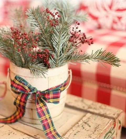 a planter with evergreens and berries and a red and green plaid ribbon is a simple and pretty traditional decoration for holidays