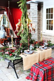 red ribbons on the table and chandelier and a red plaid blanket covering the bench give a bright festive feel to the tablescape