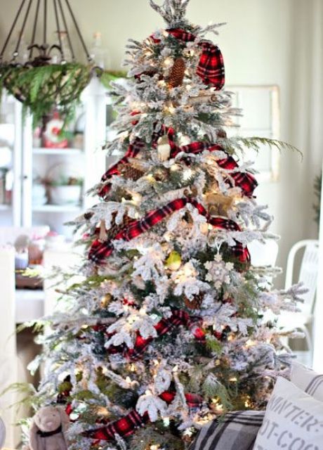 a flocked Christmas tree with metallic and colorful ornaments, red plaid ribbons, pinecones and lights looks very festive and bold