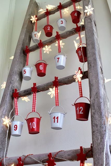 a creative advent calendar with white and red buckets hanging, with star-shaped lights and numbers on the buckets is a very cool solution
