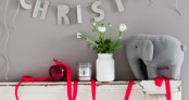 red ribbon, a red apple, a grey elephant and a grey wall with letters make up nice Christmas decor in contrasting colors