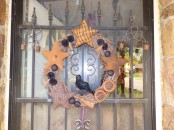 a vintage rustic Halloween wreath of vine, with fabric stars, nuts, pinecones and a crow is a bold and scary decor idea