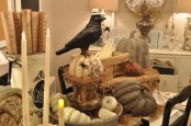 rustic Halloween table styling with candles, pumpkins, a crow on top a pumpkin, spiders and hay is chic and not very scary