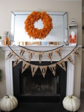 an orange feather wreath, a burlap banner and pumpkins for simple rustic Halloween decor