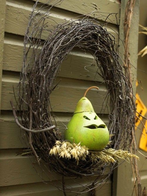 a vine wreath with wheat and a cutout pear is a cool and fun rustic Halloween decor idea