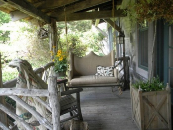 rustic patio with neutral upholstered wooden furniture, potted greenery and blooms