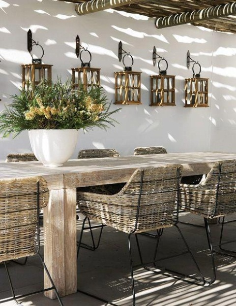 a rustic patio with wooden and wicker furniture, wooden lanterns hanging on the wall